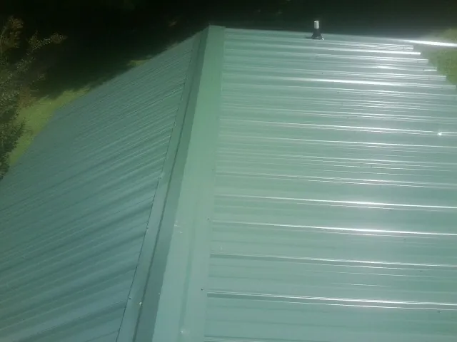 New green metal panels meeting at the ridge of a roof — Flat Roof Repair work by our crew in Beachwood