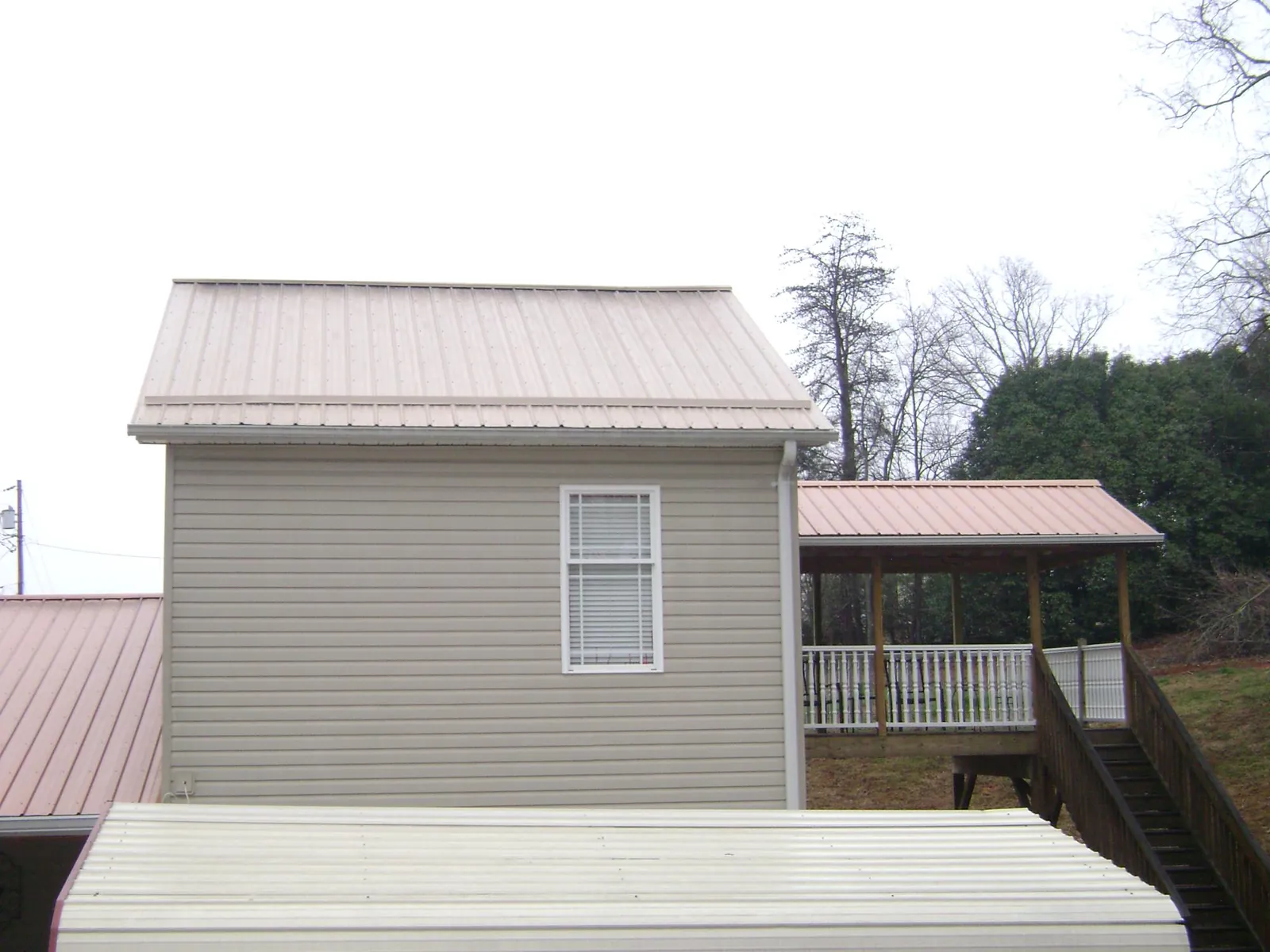 Tan metal roofs on a two story addition and attached porch, from a Roof Replacement job in Beachwood