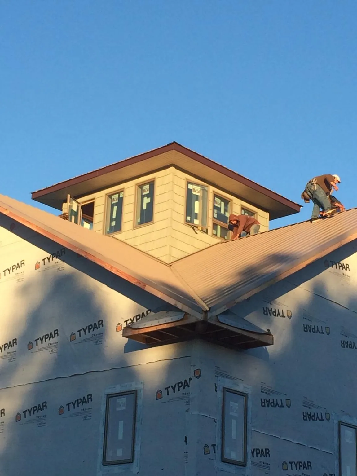 Roofers working around a rooftop cupola on a new metal roof at sunset — Roof Waterproofing in Beachwood by Roofing Brothers